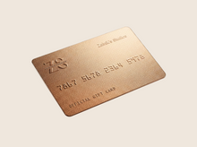 Load image into Gallery viewer, Bronze gift card with embossed text on a gray background
